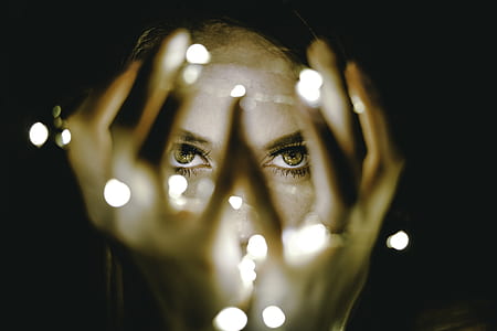 close-up photo of woman holding string lights in with black background thumbnail