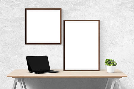 black laptop computer on table in front of two photo frames thumbnail