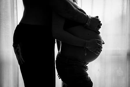 greyscale photography of man hugging a pregnant woman thumbnail