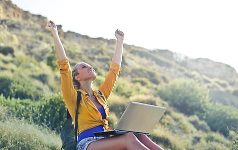 A young blonde woman in yellow button-up shirt and denim shorts sitting with her hands and face up thumbnail