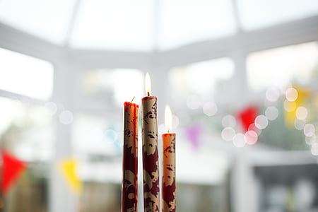 selective focus photography of three white-and-red lighted stick candles thumbnail
