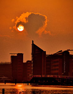 black and red concrete high-rise building near body of water at golden hour thumbnail