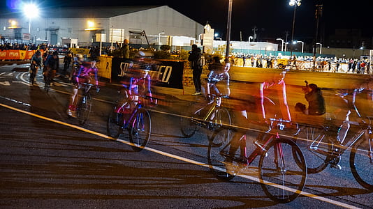 time-lapse photography of cyclist speeding on road at night time thumbnail