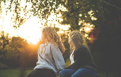 Two Women Sitting Near Green Tree during Sunset thumbnail