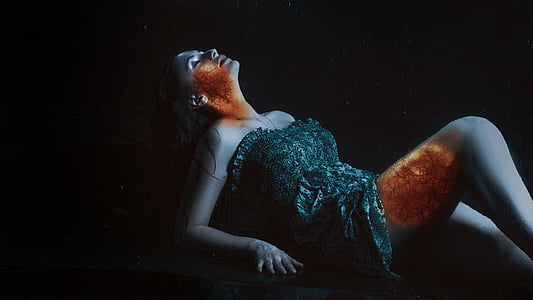 woman wearing gray strapless dress lying on black surface in dark room thumbnail