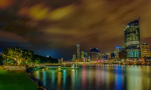panoramic view of city buildings beside body of water nighttime thumbnail