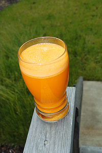 highball glass of orange drink on top of gray wooden surface thumbnail