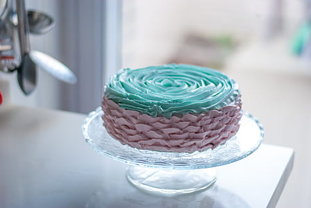 round teal and brown icing-covered cake on glass candy dish thumbnail