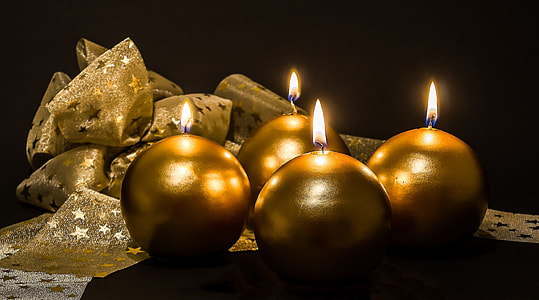 four lighted round gold-colored candles thumbnail