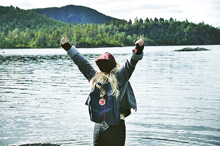 woman in green jacket spreading arms near water thumbnail