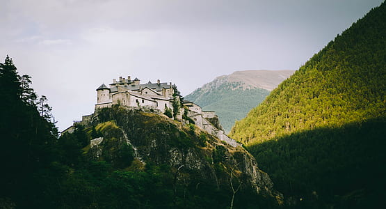 aerial photography of gray concrete castle on top of mountain under white sky at daytime thumbnail