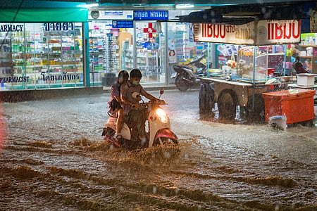 two people on motor scooter in middle of flood thumbnail