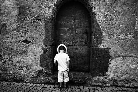 Grayscale Photo of Toddler Standing and Wearing Hat on the Ground thumbnail