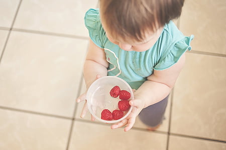 baby holding white bowl filled with raspberries thumbnail