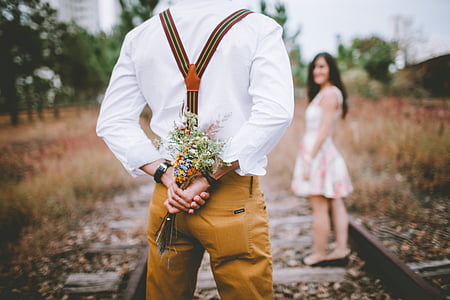 man holding flowers in front of woman during daytime thumbnail