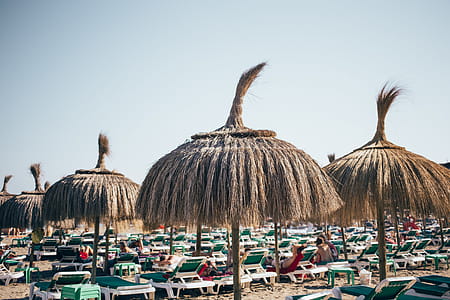 Grass umbrellas on the beach resort with relaxing tourists thumbnail