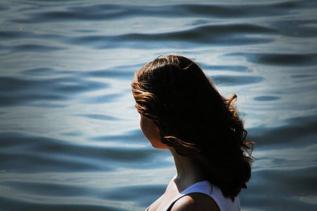 woman wearing white tank top facing ocean thumbnail