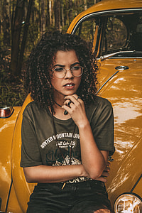 woman wearing gray t-shirt sitting on yellow beetle car thumbnail