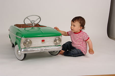 toddler with red and white striped shirt next to teal ride-on vehicle thumbnail
