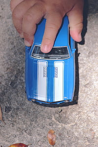 child holding blue car toy on floor thumbnail