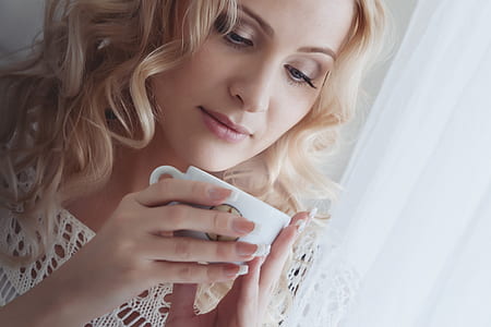 woman holding white ceramic mug near white curtain thumbnail