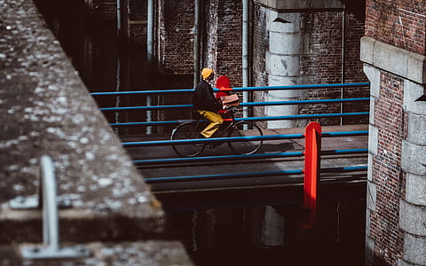 woman riding bike along concrete bridge during day thumbnail