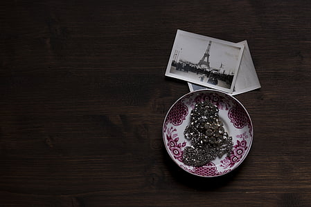silver-colored jewelry on ceramic plate beside Eiffel Tower picture thumbnail