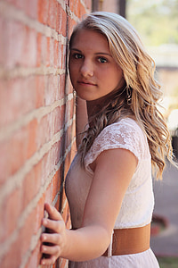 woman leaning on brown bricked wall during daytime photo thumbnail