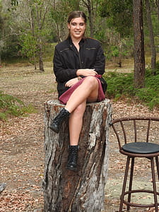 Woman Wearing Black Jacket Sitting on Tree Log Near Bar Stool thumbnail