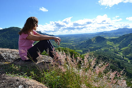 woman wearing pink t-shirt sitting above the mountain thumbnail