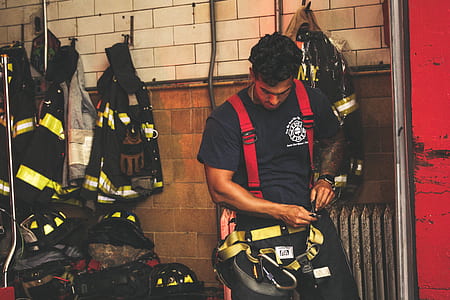 man fixing his harness near fireman uniforms thumbnail