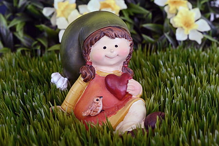 orange and yellow ceramic girl figurine on green grass field thumbnail