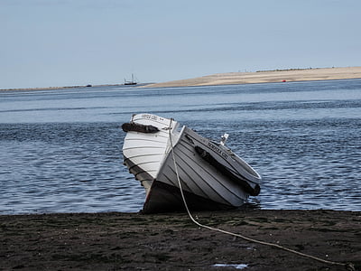 white dinghy boat on sand near body of water thumbnail