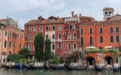 green concrete building near body of water with boats under white sky during daytime thumbnail