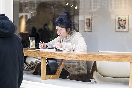 woman writing on brown wooden table thumbnail