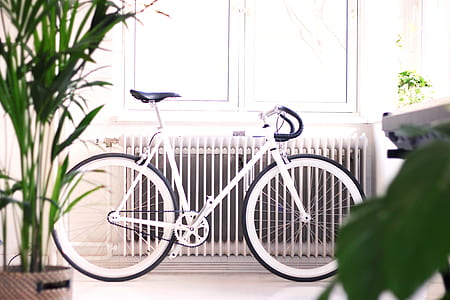 white road bike beside white radiator and window pane thumbnail