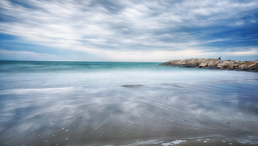 body of water near rock formation at daytime thumbnail