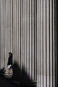 woman standing behind white concrete pillar tower thumbnail