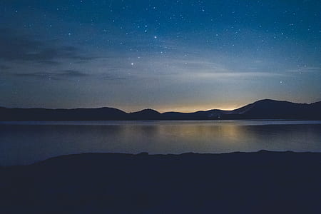 silhouette photo of a mountain and body of water thumbnail