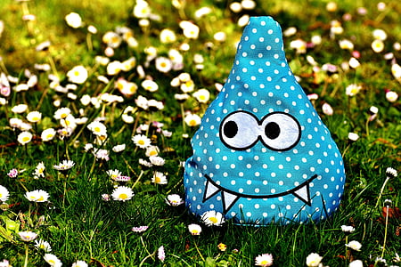 blue and white monster plush toy on daisy flowers at daytime thumbnail