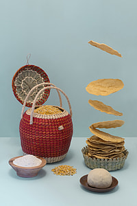 red and brown seed-filled wicker basket beside white powder-filled bowl, dough on brown saucer and round food on round brown wicker bowls thumbnail