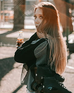 woman holding pair of inline skates and bottle of Coca-Cola thumbnail