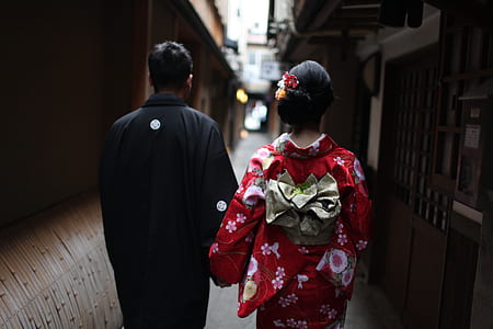 man and woman walking on pathway in between of buildings thumbnail