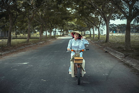 woman with hat cycling on gray road thumbnail