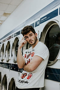 man leaning in front of clothes washer and dryer thumbnail