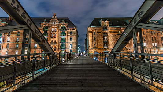 brown concrete high-rise building beside suspension bridge thumbnail