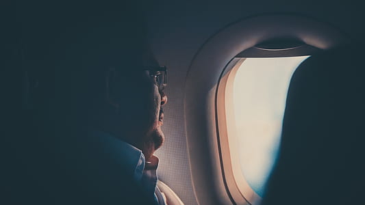 man in white collar top and wearing eyeglasses beside of airplane window thumbnail