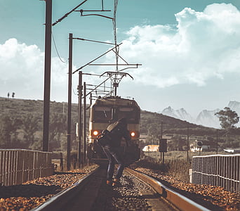 person capturing photo of moving train on railroad during daytime thumbnail