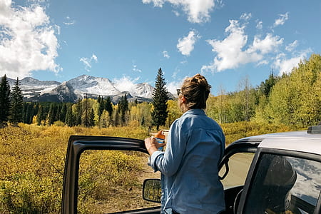woman standing outside vehicle while looking at the mountains thumbnail