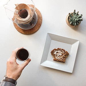 clear glass teapot on round brown particle board trivet thumbnail